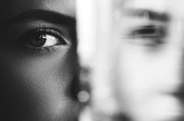 Retrato em preto e branco, metade do rosto refletida em um vidro