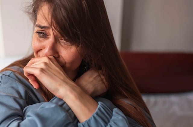 Mulher deitada, com o rosto apoiado nas mãos, em um momento de tristeza